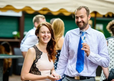 Lachende Gaeste mit Sektglas bei Hochzeitsreportage im Wirtshaus am Rosengarten, Hochzeit in Sendling-Westpark.