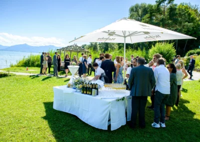 Hochzeitsfeier am Chiemsee mit Gästen, Stehtischen und Buffet im Freien. Hochzeitsreportage in Oberbayern.