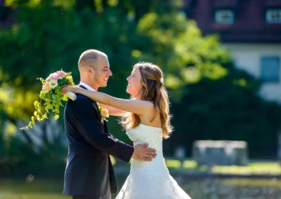 Brautpaar-Shooting im Schloss Blutenburg, Oberbayern. Paar laechelt in der Sonne, romantisch und gluecklich am Hochzeitstag.
