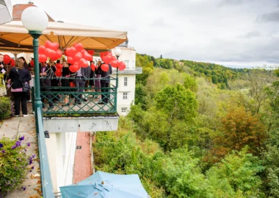 Hochzeitsfeier in Pullach mit roten Ballons auf Terrasse, im Hintergrund das Isartal, festgehalten in Hochzeitsreportage.