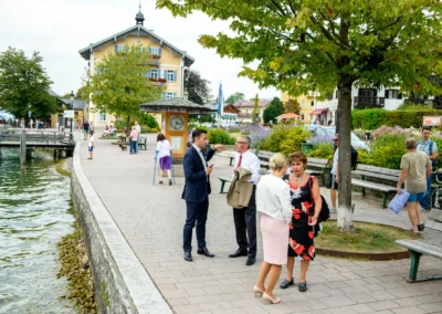 Gespraech bei einer Hochzeit in Rottach-Egern am Ufer mit Gaesten und Weg markiert Hochzeit in schoenem Ambiente.
