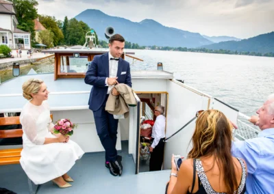 Brautpaar auf Boot in Rottach-Egern, lachend bei Hochzeit. Hochzeitsreportage auf dem Tegernsee im Seehotel Malerwinkel.