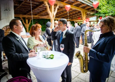 Gaste bei Hochzeitsfeier in Bad Wiessee feiern unter Herz-Luftballons mit Saxophon-Musik. Hochzeit Fotografie.