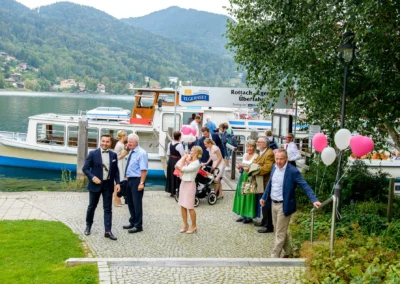 Hochzeitsgesellschaft am Tegernsee mit Schiff und Luftballons, fotografiert bei einer Hochzeit in Rottach-Egern.