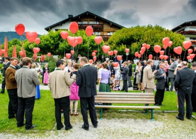 Gäste mit roten Herzballons auf einer Hochzeitsfeier in Bad Wiessee, Hochzeitsreportage südlich von München.