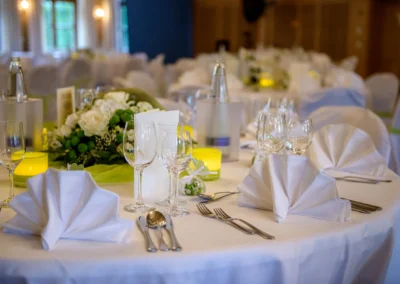 Elegantes Gedeck bei einer Hochzeitsfeier nahe Muenchen. Weiss gedeckter Tisch mit Blumenschmuck und Kerzen.