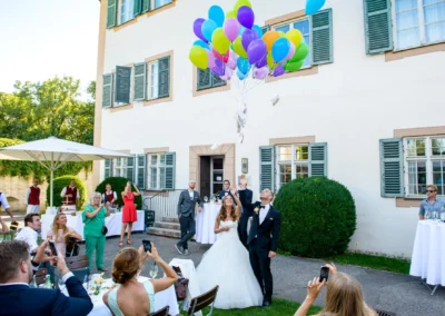 Brautpaar laesst bunte Ballons bei Hochzeitsfeier im Schloss Blutenburg, Oberbayern steigen. Hochzeitsreportage in München.