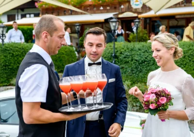 Hochzeitsreportage im Seehotel Malerwinkel, Rottach-Egern. Brautpaar mit Blumenstrauss und Getraenken.
