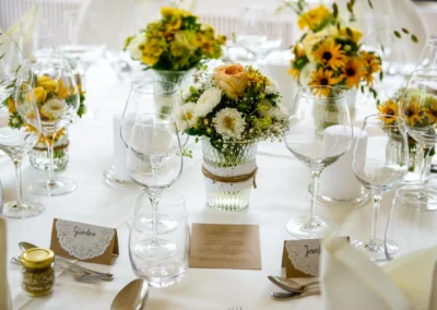 Elegante Tischdekoration mit Blumen und Gläsern bei Hochzeitsfeier im Hotel Kolbergarten, festlich und einladend.