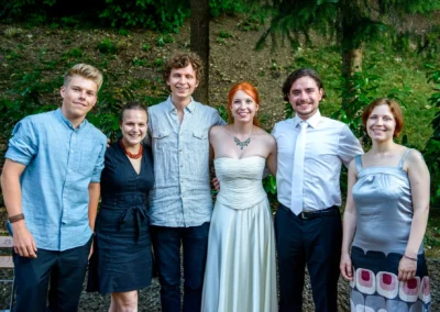 Gruppenfoto bei einer Hochzeit im Westpark, München. Braut und Gäste lächeln in die Kamera. Hochzeitsfotografie.