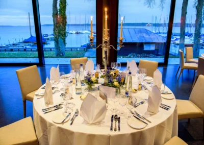 Eleganter Hochzeitstisch mit Kerzen und Blumen im Marina Resort, Starnberger See als Hintergrund.