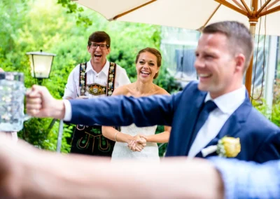 Gaste bei der Hochzeitsfeier in Bad Tolz, lachen und heben Glaser an. Hochzeitsfotograf aus Bayern dokumentiert.