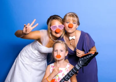 Braut mit Freunden posiert spaßig bei Hochzeit nahe München vor der Fotobox; rote Nasen und Accessoires