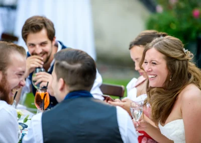 Lachende Gaeste bei einer Hochzeit in Oberbayern. Hochzeitsreportage am Schloss Blutenburg in entspannter Atmosphaere.