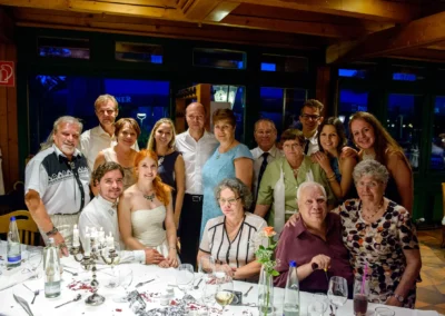Hochzeitsgesellschaft feiert bei Hochzeit in Sendling-Westpark, Brautpaar und Gaeste lachen in festlicher Umgebung.