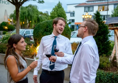 Gaste in eleganter Kleidung stoßen bei einer Hochzeitsfeier im Hotel Bauer, Oberbayern, mit Weingläsern an.