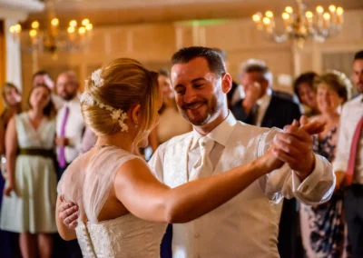 Tanzendes Brautpaar bei Hochzeit nahe Muenchen, umgeben von Gaesten im festlichen Saal. Hochzeitsfotografie in Oberbayern.
