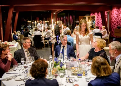 Gäste bei Hochzeitsfeier in Bernried; Braut im Gespräch, eleganter Saal, festliche Dekorationen. Hochzeitsfotografie.