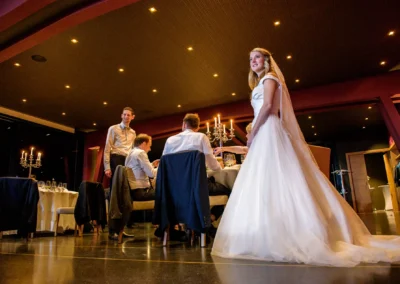 Braut bei Hochzeitsfeier im Marina Resort, elegant gekleidet, Gaeste sitzen an festlich gedecktem Tisch.