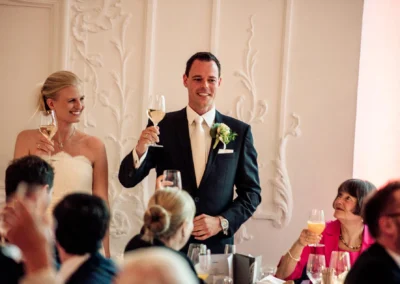 Brautpaar beim Anstoßen bei einer Hochzeitsfeier im Tegernsee Hotel, entspannte Stimmung und elegante Dekoration.