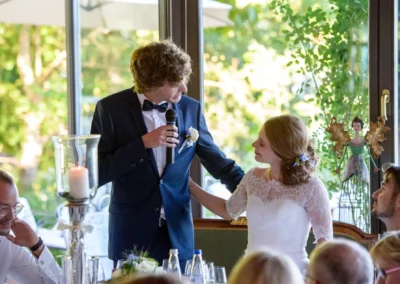Bräutigam spricht bei Hochzeit am Chiemsee, Braut lächelt, romantische Trauung in Oberbayern, Hochzeitsreportage.