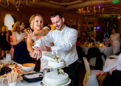 Brautpaar schneidet Hochzeitstorte bei Feier nahe Muenchen, festgehalten in lebendiger Hochzeitsreportage.