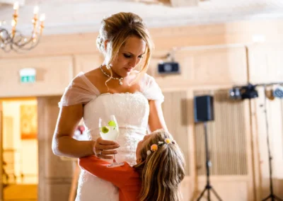 Braut bei der Hochzeit nahe München mit Kind, hält Getränk, festgehalten in einer Hochzeitsreportage im Hotel Bauer.