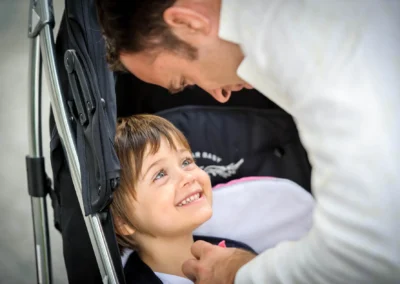 Vater beugt sich liebevoll zu lachendem Kind im Kinderwagen bei einer Hochzeitsfeier in Bad Wiessee.