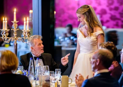 Braut bei Hochzeitsfeier spricht mit Gast; elegante Tischdeko; Hochzeitsfotografie in Bernried.
