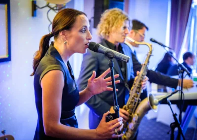 Musikerin singt bei Hochzeitsfeier im Terrassenhof, Tegernsee. Hochzeit Eventfotografie, Reportage Süddeutschland.