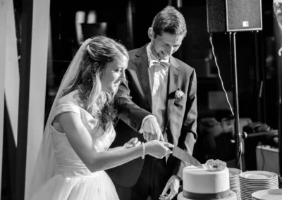 Brautpaar schneidet Hochzeitstorte bei Feier im Marina Resort. Hochzeitsfoto zeigt froehlichen Moment in Bernried.