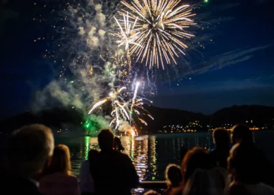 Feuerwerk bei Hochzeit am Tegernsee, abends. Hochzeitsgesellschaft schaut zu, festlich beleuchteter Himmel.