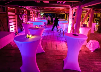 Hochzeitsfeier in Bad Wiessee, lila beleuchtetes Bootshausmit Stehtischen, bei Nacht, eventfotografie.