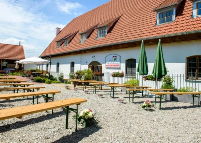 Holzbänke und grüne Schirme im Außenbereich von Gut Schloss Sulzemoos, perfekte Hochzeitslocation.