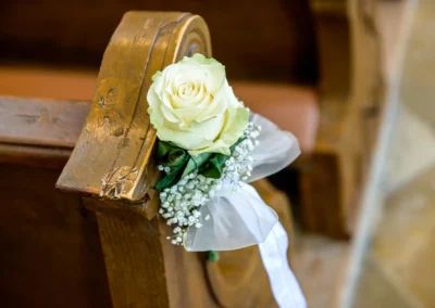 Weiße Rose auf Kirchenbank bei Hochzeitsfotografie in St. Benedikt Gelting.