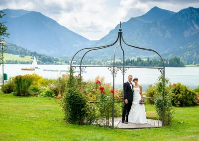 Brautpaar-Shooting am Schliersee, floristisches Pavillon, Berge im Hintergrund, Hochzeitsfotografie in Oberbayern.