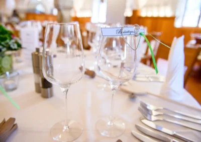 Weingläser mit Namensschild Braeutigam auf Hochzeitstischdekoration in Gut Schloss Sulzemoos fotografiert.