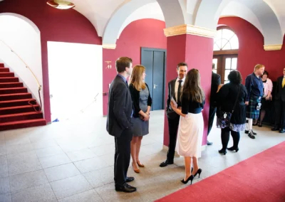 Gäste versammeln sich bei standesamtlicher Trauung im Kurhaus Bad Tölz, elegante Kleidung, rote Wände und Teppich.