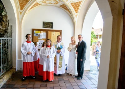 Brautpaar mit Priester und Ministranten bei kirchlicher Trauung in St. Benedikt Gelting. Hochzeitsfoto im Eingangsbereich.
