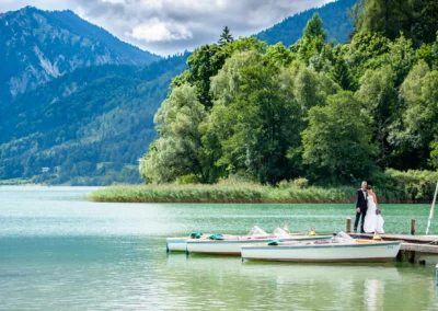 Brautpaarshooting am Seeufer mit Booten und Bergblick, Hochzeitsportraits am Schliersee in Oberbayern.