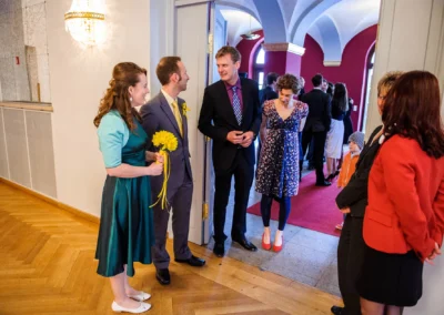 Gäste begrüßen sich während der standesamtlichen Trauung im Kurhaus Bad Tölz. Hochzeitsfoto in Innenraum.