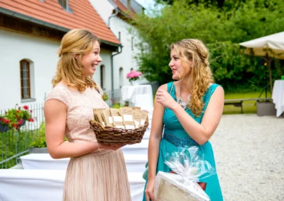Zwei Frauen unterhalten sich bei einer freien Trauung auf Gut Schloss Sulzemoos, eine mit einem Geschenkkorb.