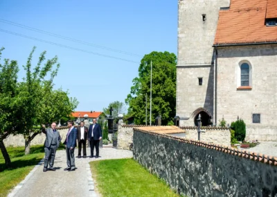 Kirchliche Trauung in Warngau, Männer in Anzügen vor Kirche. Hochzeitsfotograf zeigt Atmosphäre in Oberbayern.