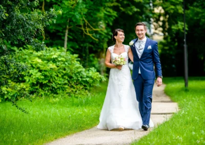 Brautpaarshooting im Park in Oberbayern, Brautpaar spaziert Arm in Arm für Hochzeitsreportage.