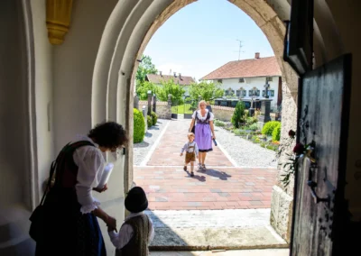 Besucher betreten die Kirche bei einer Hochzeit in Warngau. Traditionelle Tracht und Freude bei der Hochzeitsfotografie.