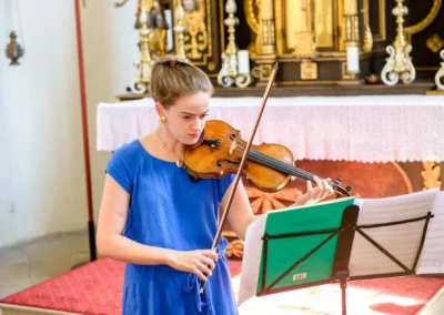 Musikerin spielt Geige bei kirchlicher Trauung in St. Benedikt Gelting. Hochzeitsfoto bei Hochzeitsfotograf in München.