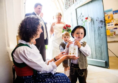 Kinder in Trachten ueberreichen Brautpaar Kerze in der Kirche. Hochzeitsfoto aus der Frauenkirche Osterwarngau.