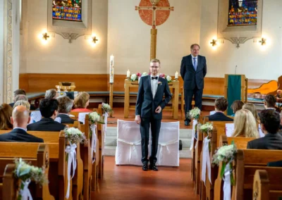 Hochzeitsfotografie in der neuapostolischen Kirche Miesbach, Braeutigam am Altar waehrend der kirchlichen Trauung.