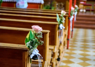 Rosen und Schleifen an Kirchenbaenken bei Hochzeitsreportage in Grosshartpenning, nahe München. Hochzeitsfotograf.