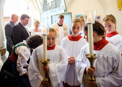 Gruppenfoto waehrend kirchlicher Trauung in Warngau mit Braut, Braeutigam und Maedchen in weissen Gewaendern.
